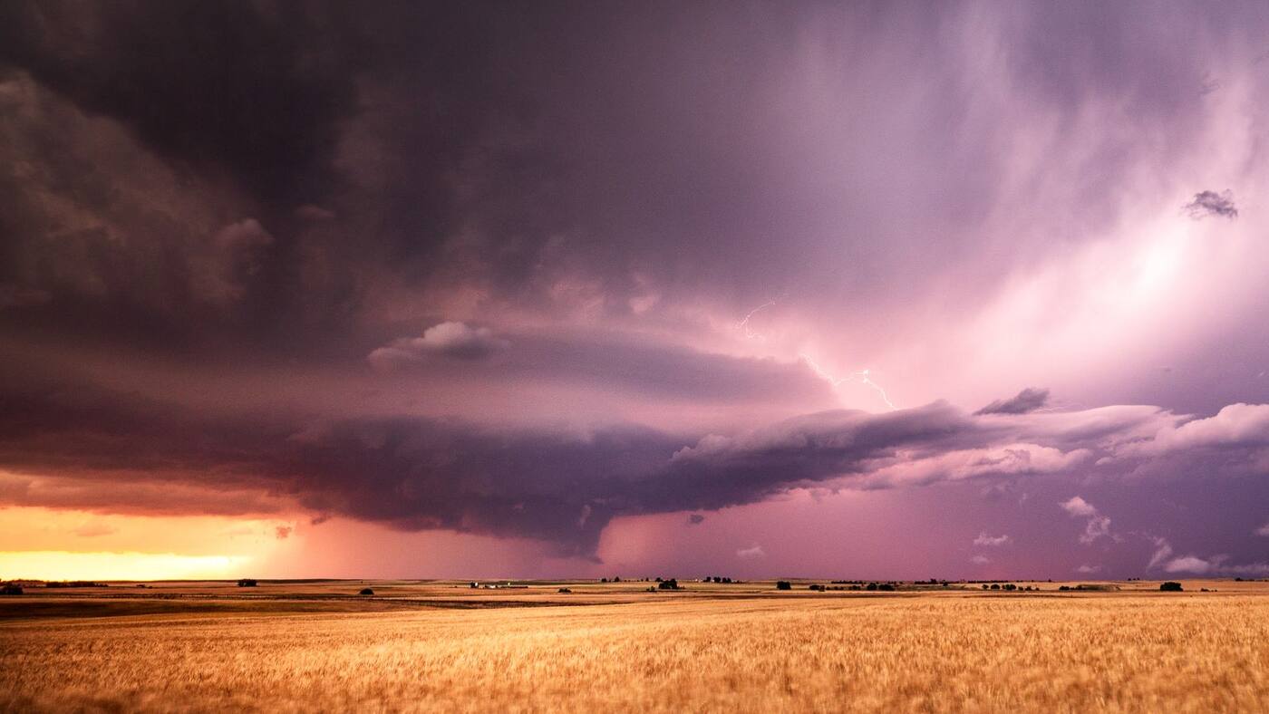 A supercell storm rolling over golden wheat fields at sunset